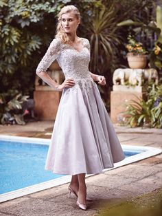 a woman standing next to a pool wearing a dress