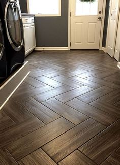 an empty kitchen with wood flooring and white appliances on the counter top, next to a washer and dryer