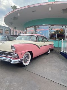 an old pink and white car parked in front of a building