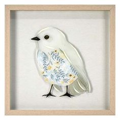 a white bird with blue and yellow flowers on it's body sitting in a wooden frame