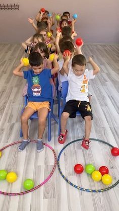 a group of children sitting in chairs with balls on top of them and one child standing behind the chair