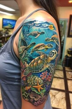 a woman's arm with an ocean scene and turtle tattoos on her left shoulder