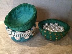 two green bowls with pearls in them on a table next to another bowl filled with balls