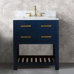 a bathroom vanity with marble top and gold faucet, against a grey wall