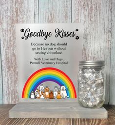 a glass jar filled with gummy bears next to a sign that says goodbye kisses