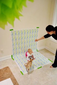 a baby sitting on top of a blanket next to a person holding a small dog