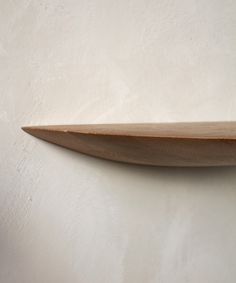 a wooden shelf on the wall with white walls in the background and light colored paint