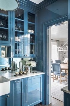 a kitchen with blue cabinets and marble counter tops, along with an open door leading to the dining room