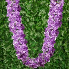 purple flowers are arranged in the shape of a letter u on a green background with shrubbery