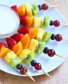 fruit skewers are arranged on a white plate