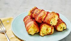 bacon wrapped in eggs on a blue plate with a fork and napkin next to it