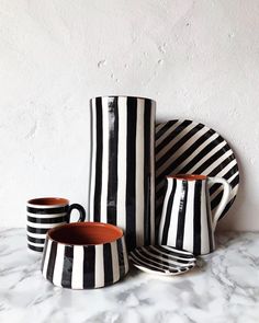 three black and white striped cups sitting next to each other on a marble counter top