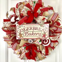 a christmas wreath with the words gingerbread bakery on it and red bows hanging from the front door