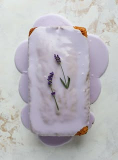 a piece of bread with lavender frosting on it sitting on top of a table