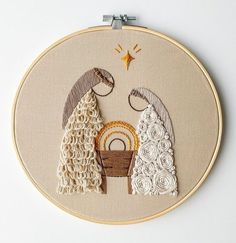 a cross stitch nativity scene is displayed in a hoop