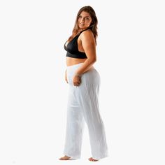 white cotton wide leg pants on a curvy model White Harem Pants For Yoga In Summer, Baggy Wide Leg Pants With Elastic Waistband For Beach, Comfortable Relaxed Fit Harem Pants For Beach, Comfortable Wide Leg Harem Pants For Relaxation, Stretch Harem Pants For Beach, Stretch Cotton Pants For Beach Season, Solid Relaxed Fit Harem Pants For Beach, White Relaxed Fit Harem Pants For Yoga, Summer Harem Pants With Loosely Fitted Hips For Relaxation