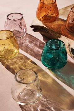 four different colored glass vases sitting on top of a table