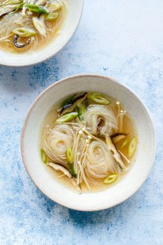 two white bowls filled with soup on top of a blue table