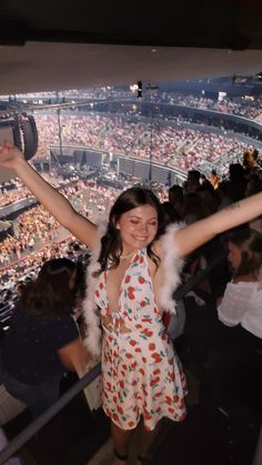 a woman standing in front of a crowd at a baseball game with her arms up