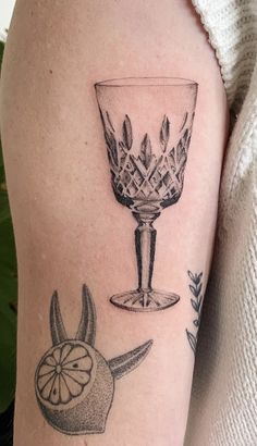 a woman with a tattoo on her arm has a wine glass and an orange slice