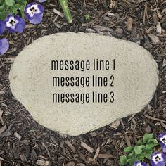 a rock with the words message line on it in front of some purple pansies