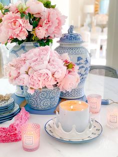 pink flowers in blue and white vases on a dining room table with tea cups