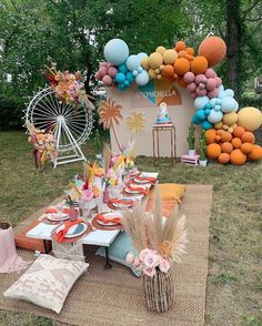 an outdoor party with balloons and decorations on the grass, including plates and napkins