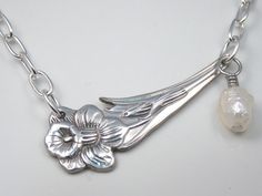 a close up of a necklace with a flower and a ball on the end of it