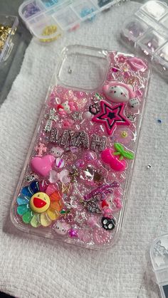 an iphone case with hello kitty and other items on it sitting on a white cloth