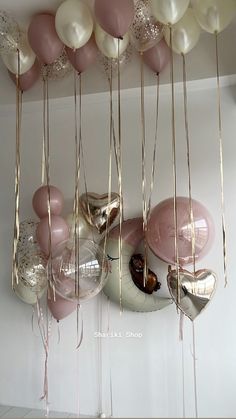 balloons are hanging from the ceiling with gold and pink streamers on them, along with other balloons