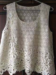 a white crocheted top hanging on a rack