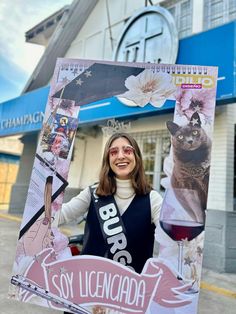 a woman standing in front of a building holding up a photo frame with a cat on it