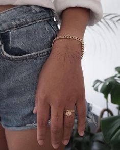 a person wearing a gold chain bracelet and a starburst ring