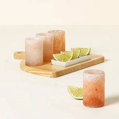 three different types of candles and limes on a tray next to some slices of lime