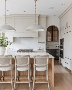 a kitchen with an island and four chairs in front of the counter top, surrounded by white cabinets