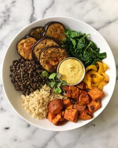 a white bowl filled with different types of food on top of a marble countertop