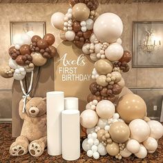 a teddy bear sitting next to balloons and a sign that says, it's first birthday