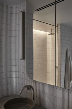 a bathroom sink sitting under a mirror in front of a shower stall next to a wall mounted towel dispenser