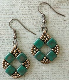 earrings with green beads on them sitting on top of a piece of paper