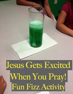 a glass filled with green liquid sitting on top of a table next to two children