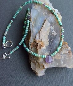 "Chrysoprase and Amethyst Necklace This beaded necklace boasts glorious earthy greens and muted purples, with its combination of chrysoprase and amethyst gemstones. Faceted rondelles of chrysoprase, in all of its natural shades, encircle the neck, sparked with randomly placed amethyst beads. Teardrop amethyst focal pendant. Finished with a sterling silver toggle clasp and findings. Small beads measure about 3.5-4.0mm, and the amethyst drop measures about 11x13mm. Necklace shown measures 18\" in Bohemian Lavender Hand-strung Jewelry, Bohemian Chrysoprase Gemstone Bead Necklaces, Bohemian Chrysoprase Gemstone Bead Necklace, Bohemian Chrysoprase Necklace With Gemstone Beads, Bohemian Amethyst Gemstone Beaded Necklace, Bohemian Amethyst Gemstone Beads, Hand-strung Amethyst Necklace For Gifts, Purple Bohemian Stone Necklaces, Bohemian Lavender Crystal Gemstone Necklace