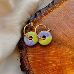 two earrings sitting on top of a piece of wood