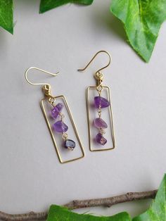 earrings with amethyst beads on them sitting on top of a leafy branch