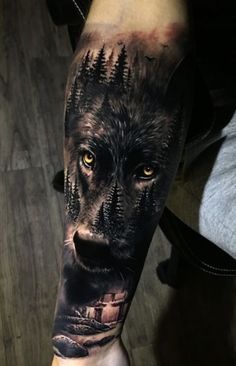 a man's arm with a wolf and trees tattoo on the left side of his arm