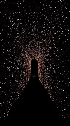 the silhouette of a person standing in front of a tunnel filled with lights at night