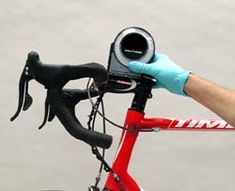 a person in blue gloves is on a red bike with a camera attached to the handlebars