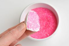 a hand holding a marshmallow over a bowl of pink food