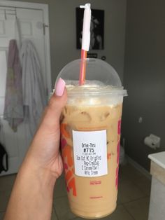 a person holding up a drink with a straw in it's mouth and a sticker on the lid