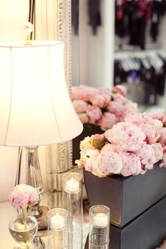 pink flowers and candles are sitting on a table next to a mirror with a lamp