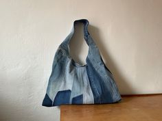 a denim bag sitting on top of a wooden table next to a white painted wall